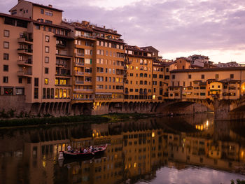 Buildings by canal against sky in city