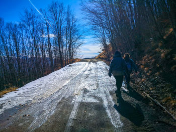 Rear view of people walking on footpath during winter