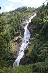 Scenic view of waterfall in forest against sky