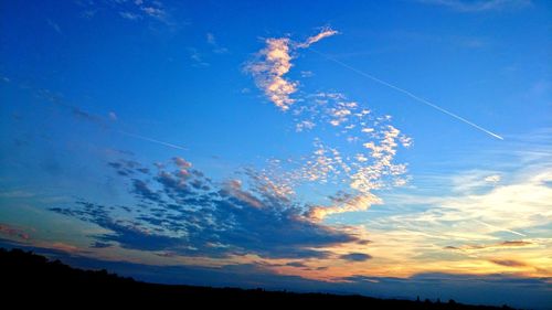 Low angle view of vapor trail in sky during sunset