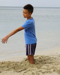 Happy boy standing on beach against sea