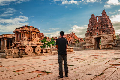 Rear view of man visiting temple against sky