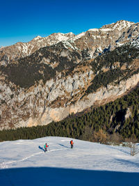 People on snowcapped mountain against clear sky