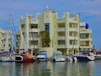 Sailboats moored on harbor by buildings in city