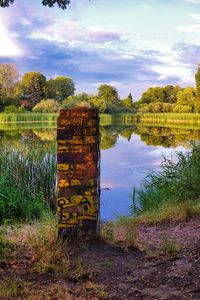 Scenic view of field by lake against sky