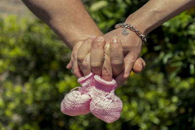 Cropped image of couple with baby booties holding hands