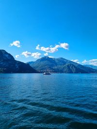 Scenic view of sea and mountains against blue sky