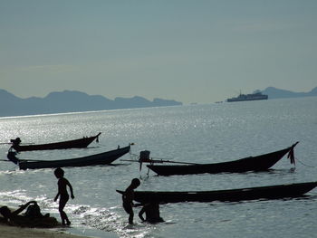 People on boat in sea against sky