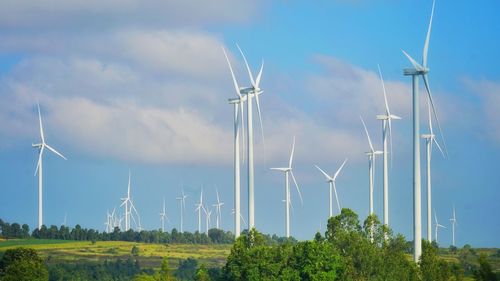 Wind turbines on field against sky