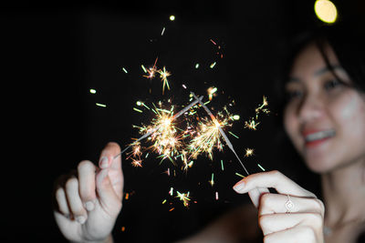 Midsection of woman holding sparkler at night