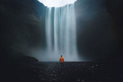 Rear view of man standing against waterfall