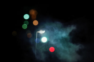 Low angle view of illuminated lights against sky at night