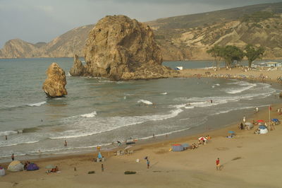 Group of people on rock by sea against sky