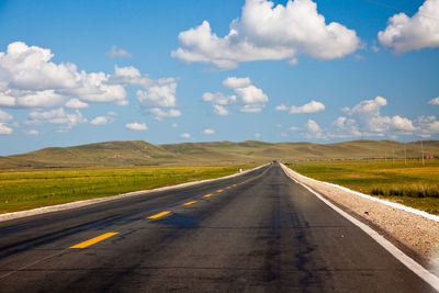 Empty road along landscape against sky