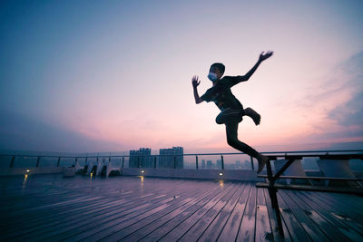 Boy jumping on floor against sky