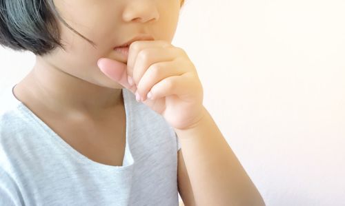 Close-up of woman holding hands over white background