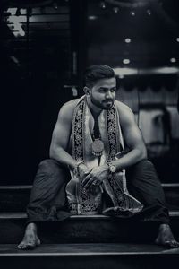 Young man sitting against wall