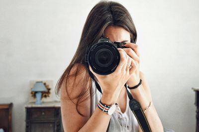 Close-up of woman photographing with camera at home