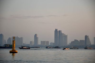 Boats in sea against buildings in city