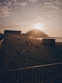 People on beach against sky during sunset