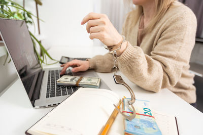 A woman with handcuffs and a laptop pays taxes