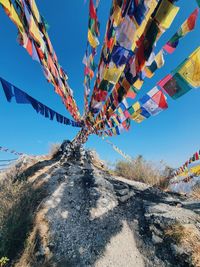 Low angle view of multi colored flags hanging on mountain against sky