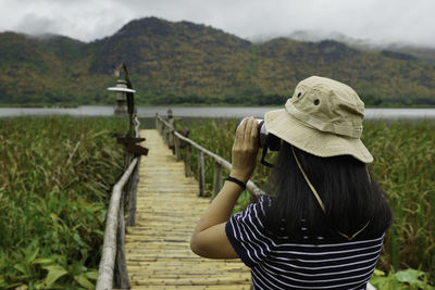 Rear view of woman photographing while standing on pier