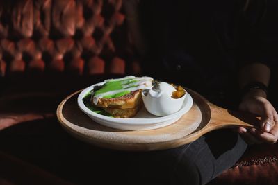 Close-up of hand holding breakfast in tray at home