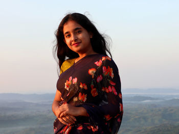 Young woman looking away against sky during sunset