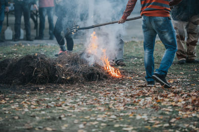 Low section of man burning hay on field