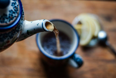 Close-up of kettle pouring tea in cup