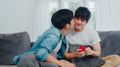 Gay man kissing partner while siting on sofa