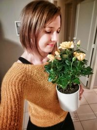 Beautiful woman by potted plant at home