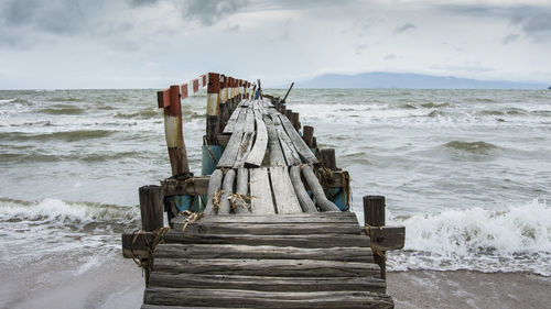 Wooden posts on beach against sky