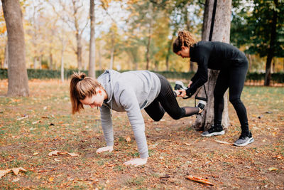 Friends exercising by trees in park during autumn