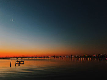 Silhouette people on beach against clear sky during sunset
