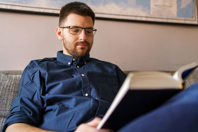 Man reading book sitting at home