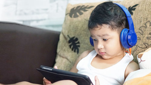 Cute boy looking at camera while sitting on mobile phone