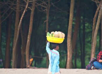 Side view of woman with umbrella against trees