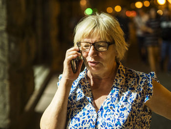 Light falling on senior woman talking on mobile phone at night