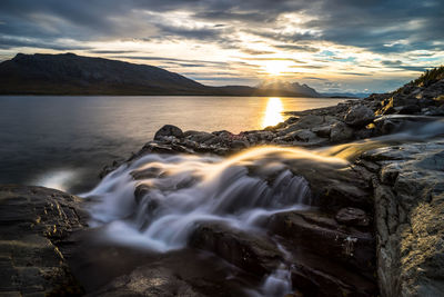 Scenic view of sea against dramatic sky during sunset