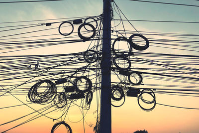 Low angle view of silhouette electricity pylon against sky