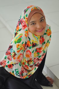 Portrait of teenage girl wearing headscarf while sitting indoors