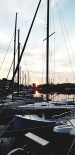 Boats moored in harbor at sunset