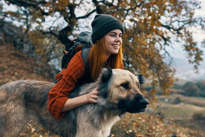 Portrait of woman with dog standing against plants