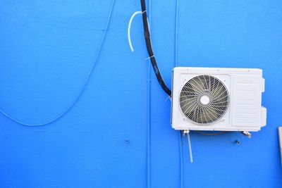 Close-up of electric lamp against blue wall