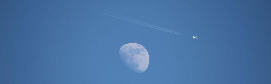 Low angle view of half moon against blue sky