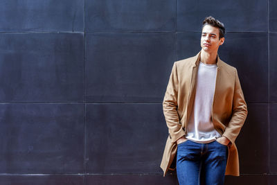 Portrait of young man standing against wall