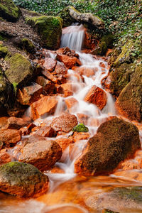 Detail of the mineral springs. cascade on stream of mineral water with ferric mud on green stones