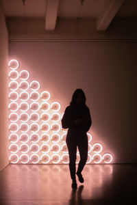 Rear view of woman standing against illuminated lights